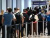 Un viaggiatore distribuisce bicchierini di vodka in una massiccia fila alla TSA tra le code e i ritardi degli aeroporti statunitensi