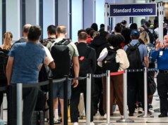 Un viaggiatore distribuisce bicchierini di vodka in una massiccia fila alla TSA tra le code e i ritardi degli aeroporti statunitensi