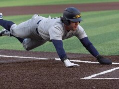 Il lanciatore di baseball del faculty spinge fuori il corridore sul tag, facendo liberare le panchine