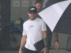 Il miliardario Adrian Portelli chiede al personale di portare la sua valigia e l’ombrello mentre lascia la Gold Coast dopo la festa di Buck